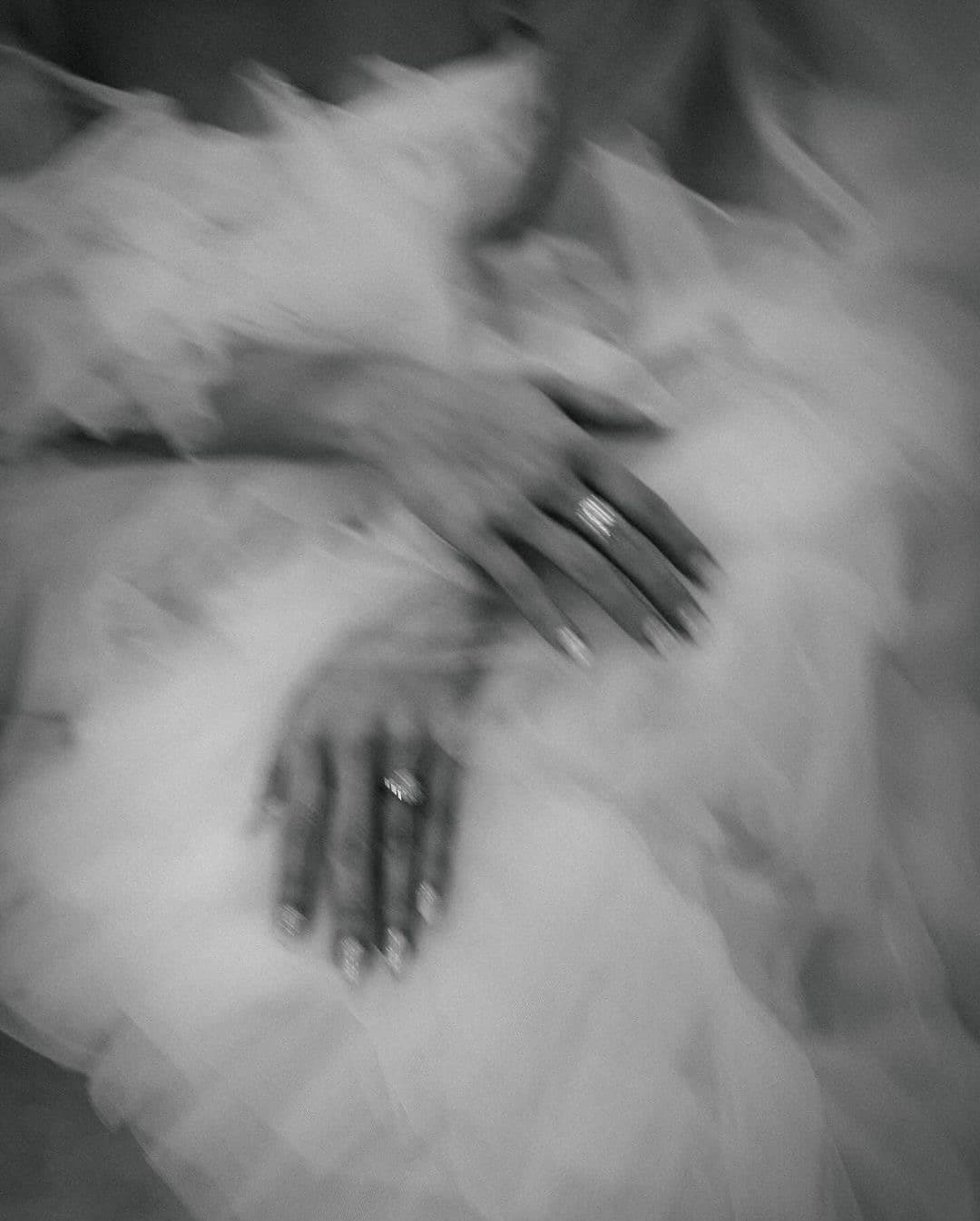 Mãos com alianças sobre camadas de tule